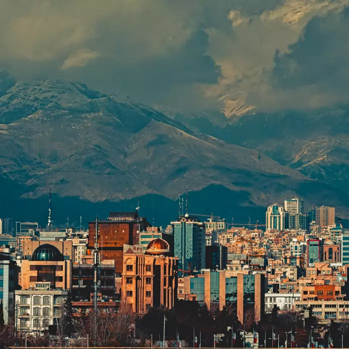 Tehran skyline with cloudy mountains in the background.